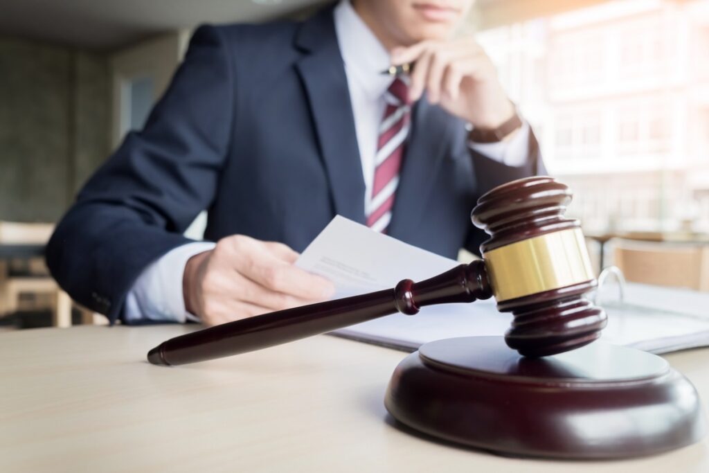 Lawyer in a suit reviewing documents with a gavel on the desk.