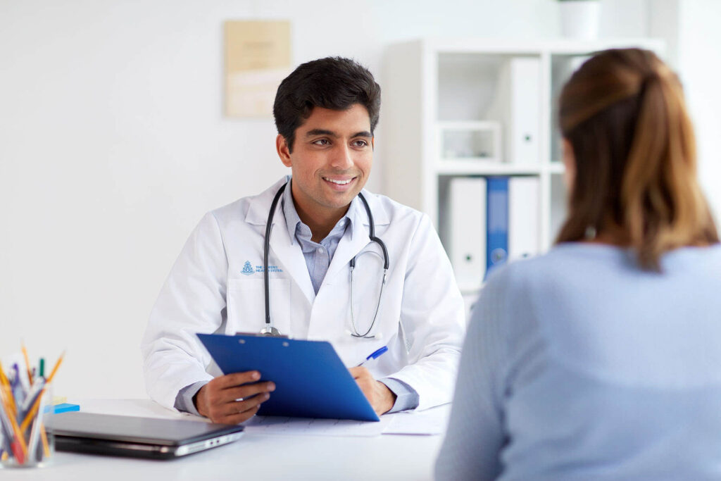 Doctor holding a clipboard while speaking with a patient.